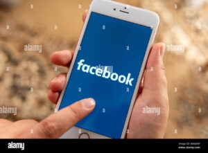 mano usando celular con icono facebook