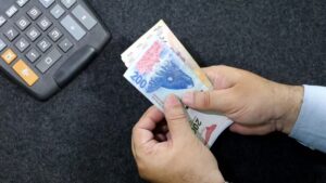 manos contando billetes argentinos con calculadora
