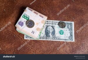 monedas argentinas y dolares con billetes apilados